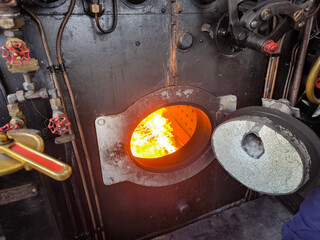 Interior de uma cabine de uma locomotiva antiga a carvão com a fornalha em chamas © LuIvDa