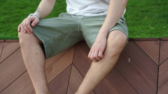 A man sits on a bench in the park and scratches his leg after being bitten by a mosquito.
A man scratches his leg.
Redness after an insect bite.
Allergic reaction.
Skin problems, dermatitis