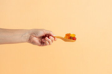 Colorful candies, jelly and marmalade with spoon in hand on cream background. 