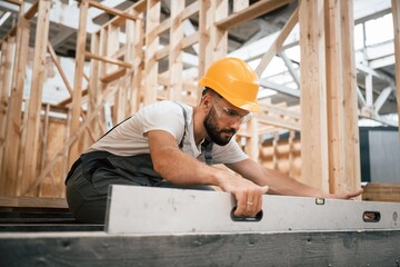 Fototapeta premium Checking the straight by using leveling tool. Industrial worker in wooden warehouse