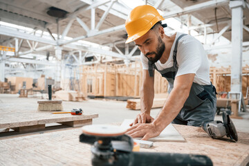 By the table. Industrial worker in wooden warehouse