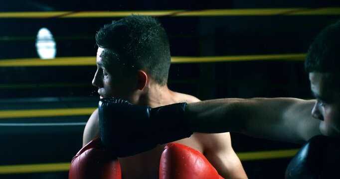 Super slow motion close up of determined  young sporty muscular shirtless male boxers fisting and punching boxing workout training to achieve victory on competition at fighting ring at 1000 fps.
