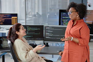 Side view shot of diverse group of two larger-bodied cheerful software developers smiling, while...