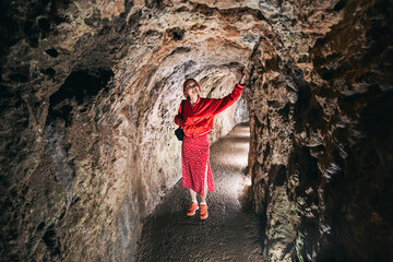 Obraz premium A woman explores a unique karst cave, standing amidst illuminated stalagmites and stalactites, immersed in the ancient geological beauty underground.