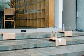 Empty Sidewalk Cafe With Wooden Furniture And Colored Water Glasses On Tables