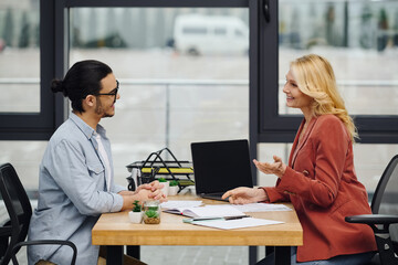 A man and woman engaged in a conversation at a table in the office.