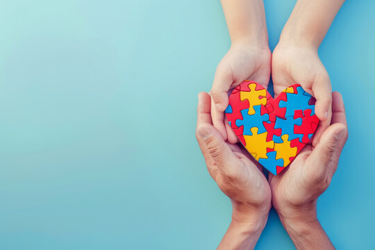 World autism awareness day concept. Adult and child hands hold heart shaped puzzle piece isolated on empty blue background with space for text or inscriptions
