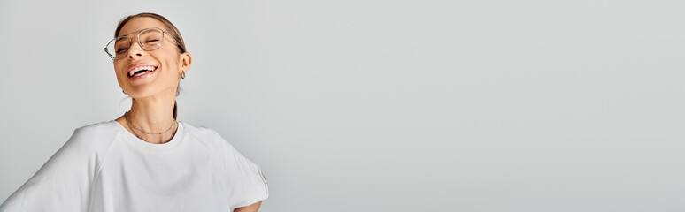A young woman wearing glasses and a white shirt poses against a grey background, exuding a sense of...