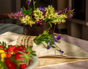 Spring forest flowers, strawberries and napkin on the table