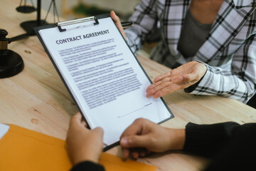 In a lawyer's office, a businessman consults an attorney for legal advice on a contract. The gavel symbolizes authority and justice. The lawyer explains the legislation and provides guidance on the ag