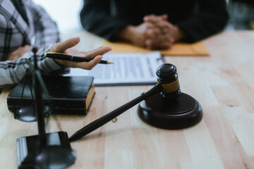 In a lawyer's office, a businessman consults an attorney for legal advice on a contract. The gavel symbolizes authority and justice. The lawyer explains the legislation and provides guidance on the ag