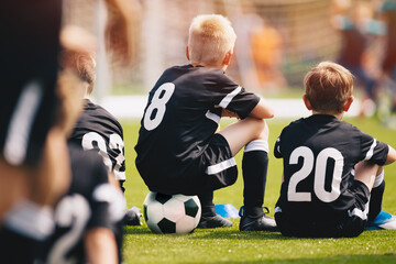 Naklejka premium Youth soccer football team. The soccer team is practicing penalty kicks. Group photo. Soccer players sitting together at training. Teammates at youth soccer league game