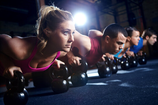 Fitness, push up and group of people with dumbbells, support and commitment to body workout. Bodybuilder, men and women together in exercise class with kettlebell, power training and teamwork in gym