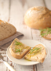 A loaf of rye bread with oil and rosemary in rustic style	