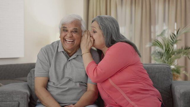 Happy Indian old wife telling a secret to her husband in ear