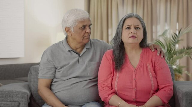 Sad Indian old couple watching TV