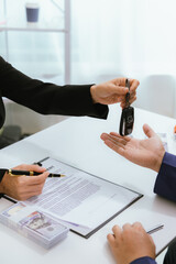 A customer signs a rental agreement for a new car at a dealership. The salesman explains the finance options and insurance details. With the paperwork complete, the keys are handed over, sealing the d