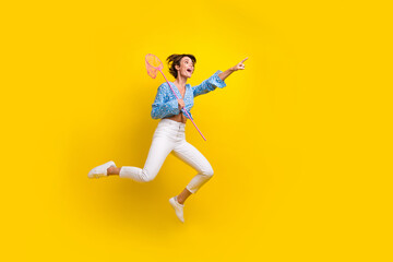 Obraz premium Full length photo of charming girl hold butterfly net jumping look directing at sale empty space isolated on yellow color background