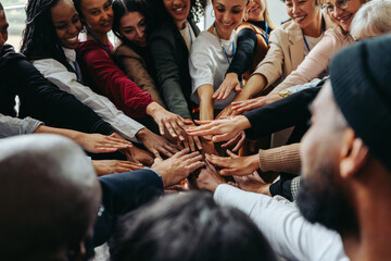 Diverse coworkers putting hands in for a unified team huddle at work