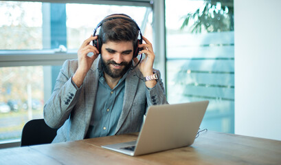 Smiling male customer support agent of call center with headset working in office.