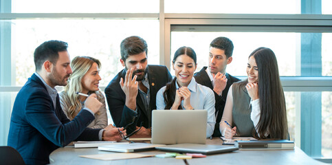 Employees in a modern office using laptop for research and teamwork, fostering collaboration and connectivity.