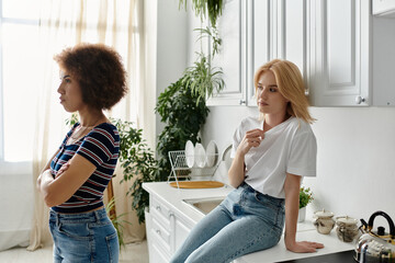 Two women, seemingly a couple, stand in their kitchen engaged in a heated argument, expressing displeasure and misunderstanding.