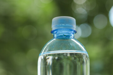  Stationary plastic cap on a bottle.water in a plastic bottle. trees with a blurred background .  Using wallpaper for package.abnormal heat.High quality photo .close up
