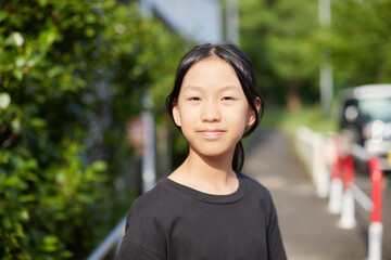 夏の住宅地の敷地で楽しく歩く一人の小学生の女の子の姿