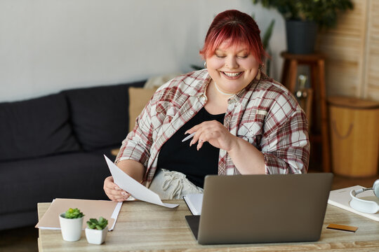 A woman sits at a desk, reviewing paperwork while smiling.