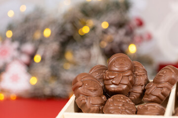 Chocolates in the shape of Christmas figures on the background of a flashing garland