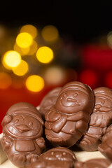 Chocolates in the shape of Christmas figures on the background of a flashing garland