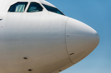 A close-up view of the cabin of a wide-body passenger jet in sunny weather. The cabin windows are covered with sun protection from the inside.