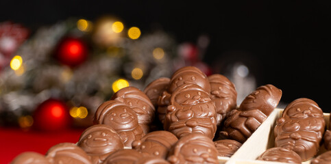 Chocolates in the shape of Christmas figures on the background of a flashing garland