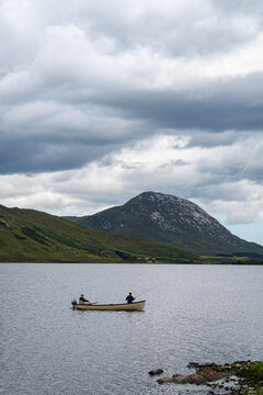 fisherman in a boat fishing on a mountain lake