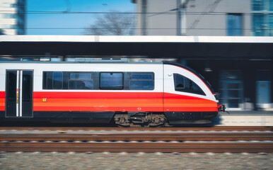 Fototapeta premium High-speed passenger train moving at railway station at sunset