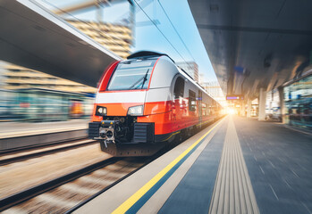 Fototapeta premium High-speed passenger train moving at railway station at sunset