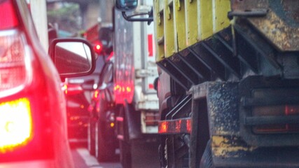 Fototapeta premium Close up photo of a back lamp of car that stuck in a traffic jam on the highway, with a bokeh background.