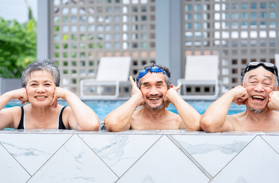 Three of senior people posing at camera at poolside,healthy elderly family and friend enjoy swimming in resort and spa on summer trip