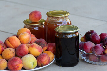 Fresh berries of blackberries, peaches and plums and jars of home-preserved sweet jam
