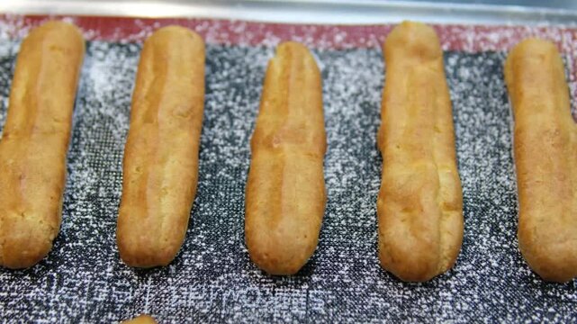 bake eclairs Freshly Baked Eclairs Lined Up in Display at a Pastry Shop. Close-up view of fresh, golden eclairs filled with creamy custard, showcased in a pastry shop. Perfect for dessert enthusiasts.