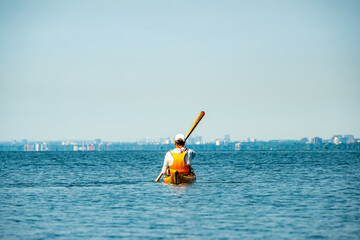 kayaking on the lake: rearview of sea kayaker on open lake ontario with a wooden greenland style paddle room for text shot off the toronto islands in summer © Michael Connor Photo