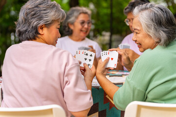Group of Happy Asian senior mature women relax and enjoy indoor lifestyle meeting party together at home. Elderly retired woman friends having fun playing card together at home garden in summer day.