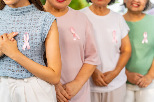 Breast Cancer Awareness Charity Concept. Group of Smiling Asian senior mature and adult women wearing T-Shirts with breast cancer symbol pink ribbon on the left.