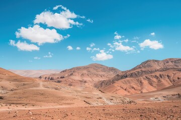 Fototapeta premium Vast and endless desert mountains under a blue sky with white clouds