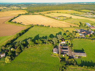 Aerial view of a former dairy farm seen in the heart of the Essex, UK countryside. Farm buildings, barns can be seen. The paddocks are still owned by the farmer.