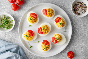 Deviled eggs with cheese, mustard and microgreens on top on a plate for Easter.