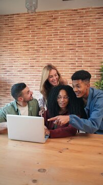 Vertical Group of young adult friends having fun using a laptop sharing on the social media. Happy multiracial people browsing online with a computer. Couples watching videos with a notebook at home