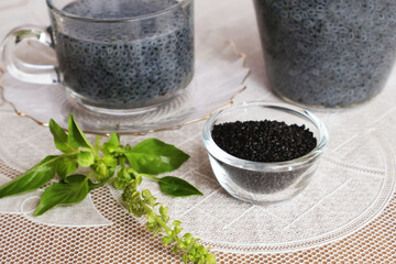 Black Basil Seeds in a glass cup placed in front of The glass has a handle and a pitcher for puffing tablets, ready to drink. Put it on a white plastic tabletop.


