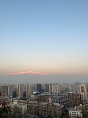 Fototapeta premium Skyline of Santiago, Chile, with the Andes Mountains in the background during a hazy winter sunset.
