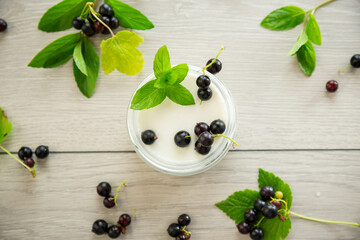 homemade sweet yogurt in a jar with black currants, on a wooden table